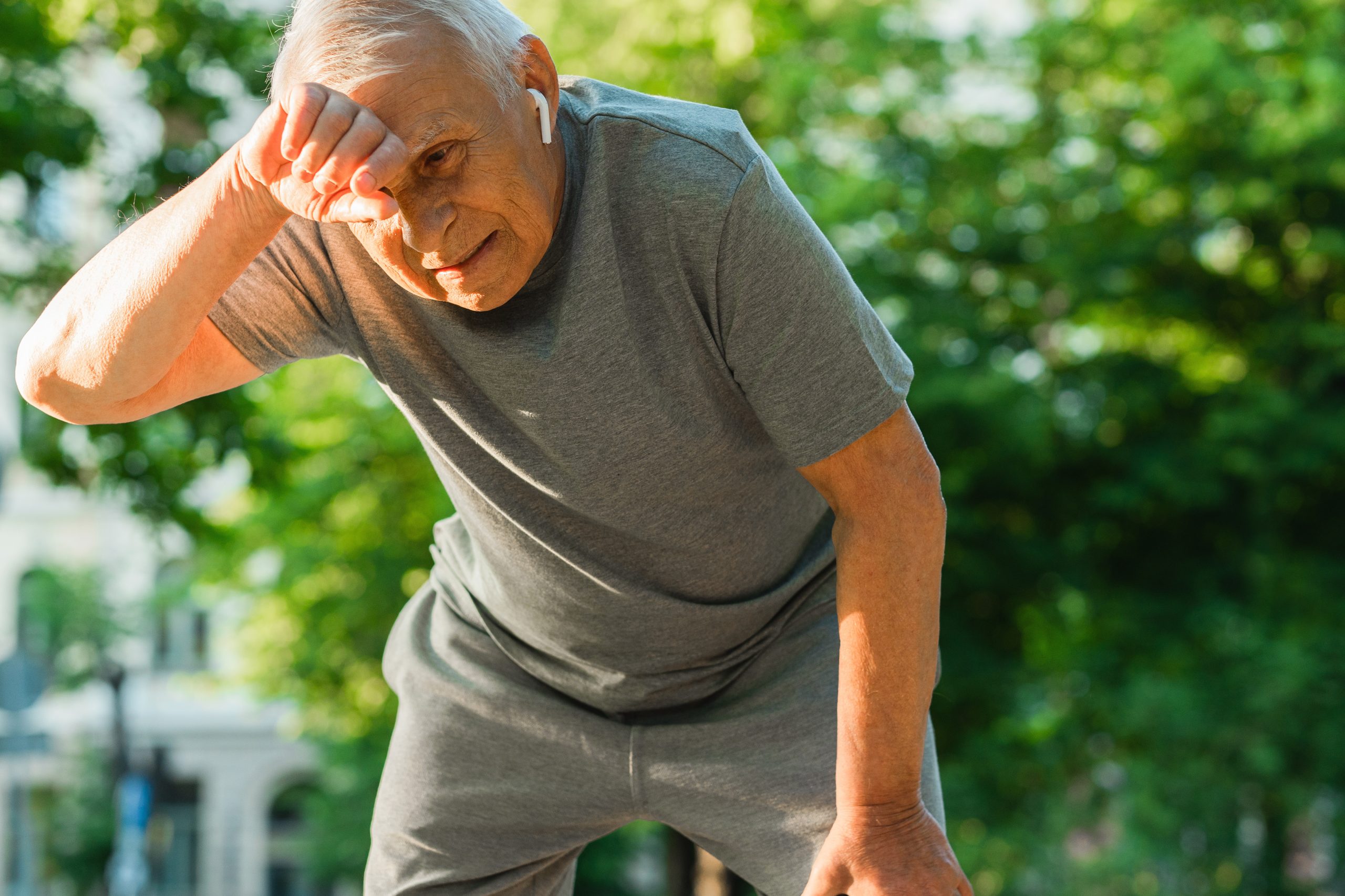 Exhausted elderly man after his jogging workout in a city park